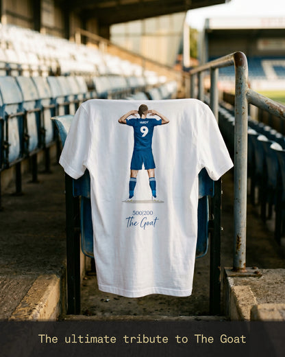 Jamie Vardy 500 Appearances 200 Goals Legacy T-shirt displayed on a stadium seat, featuring Vardy’s iconic celebration illustration and signature “500|200 The Goat” artwork on the back.